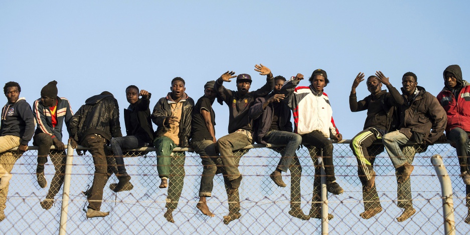 Migranti africani siedono in cima ad una recinzione di confine durante un tentativo di attraversare territori spagnoli, tra Marocco e l'enclave nord africana di Melilla, il 22 ottobre 2014. Credit: Jesus Blasco de Avellaneda /Reuters